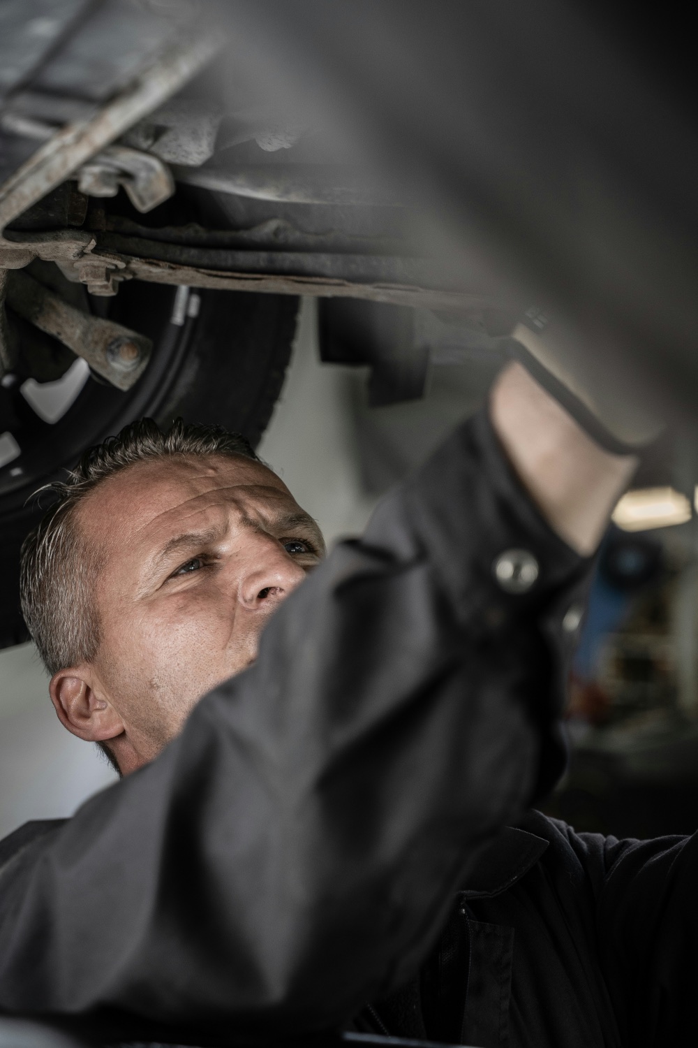 Mechanic inspecting underside of vehicle